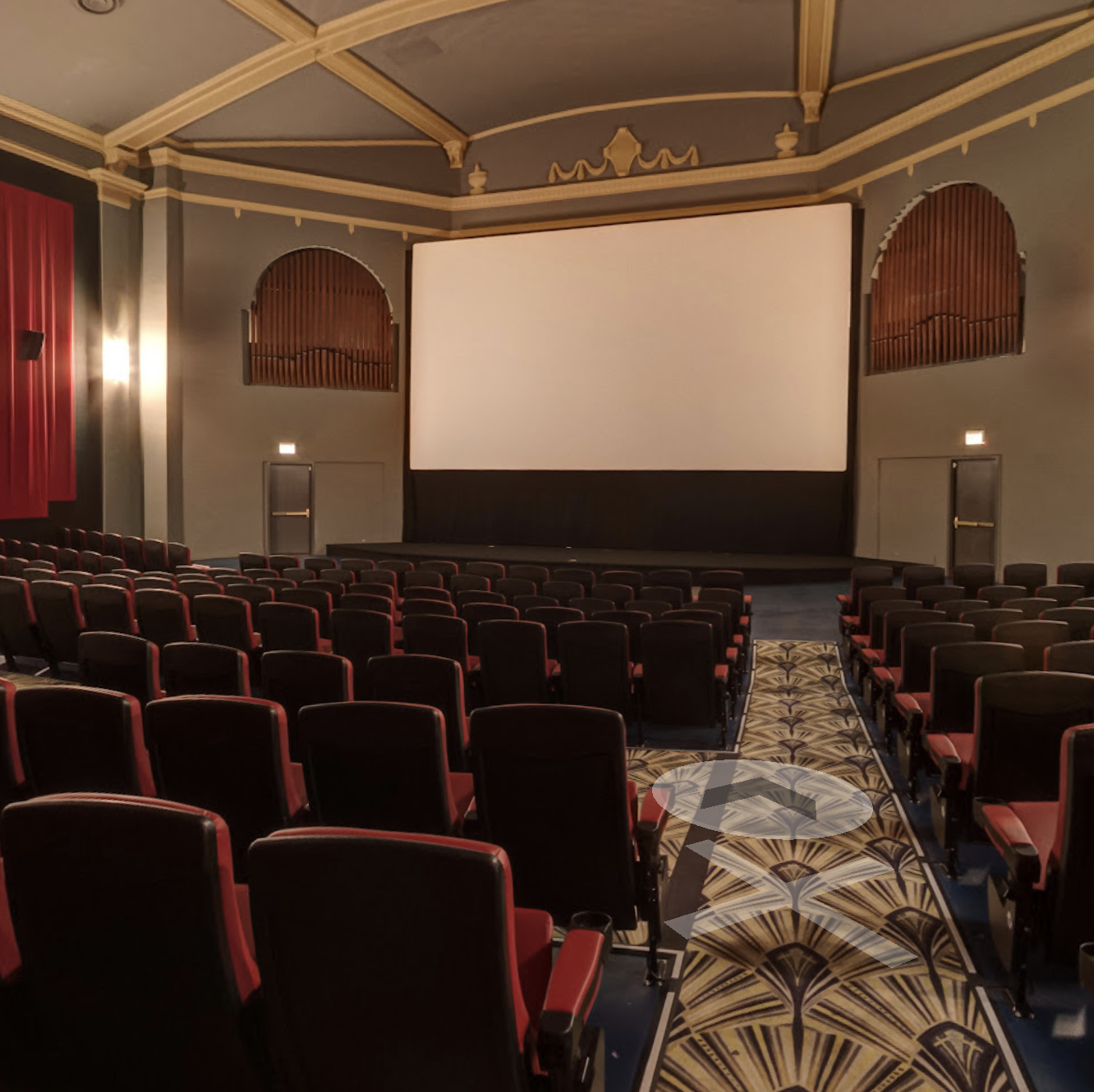 View of classic old school movie theater screen with rows of seats in front