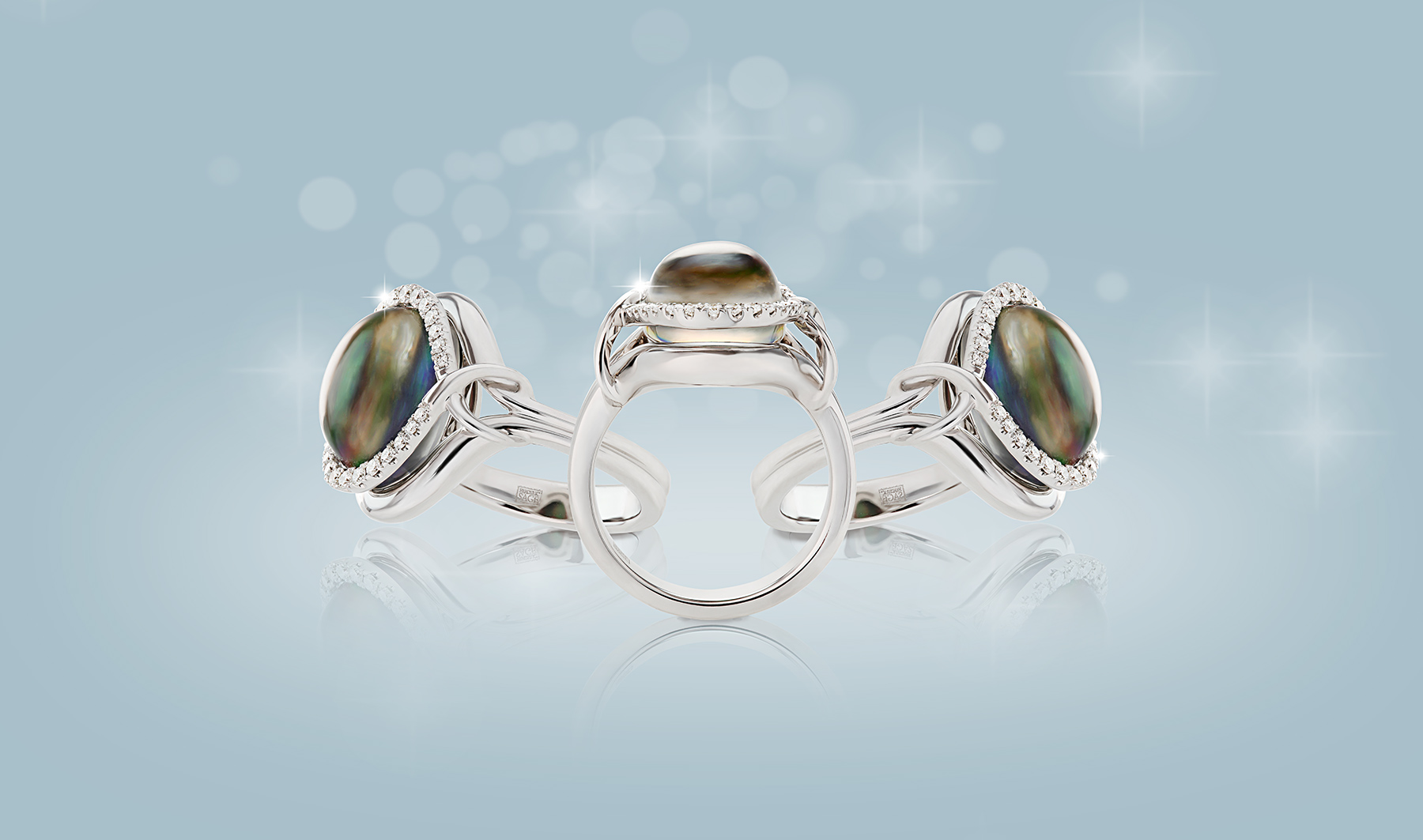 composite shot of 3 opal rings in silver settings on blue background with white bokeh